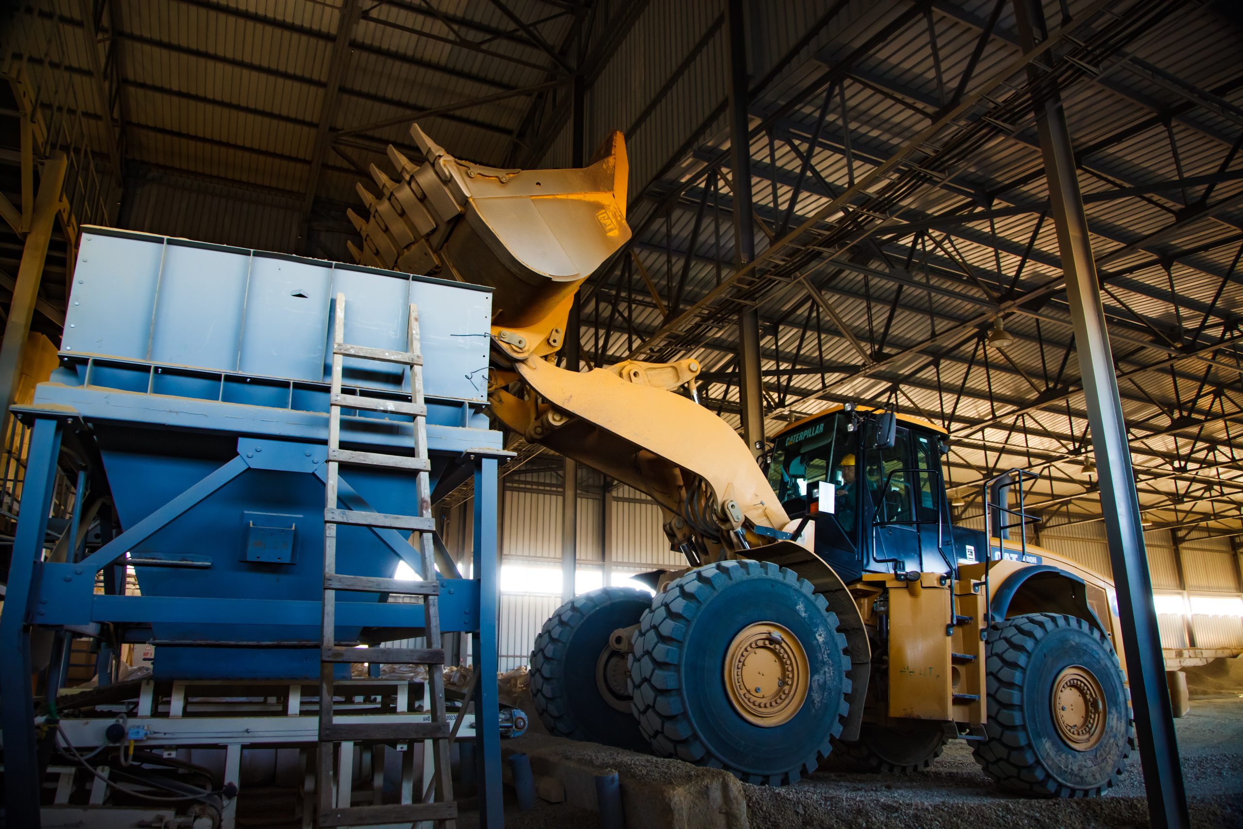 Phosphate fertilisers plant. Caterpillar excavator (bulldozer) loading minerals in machine hopper loader for processing.